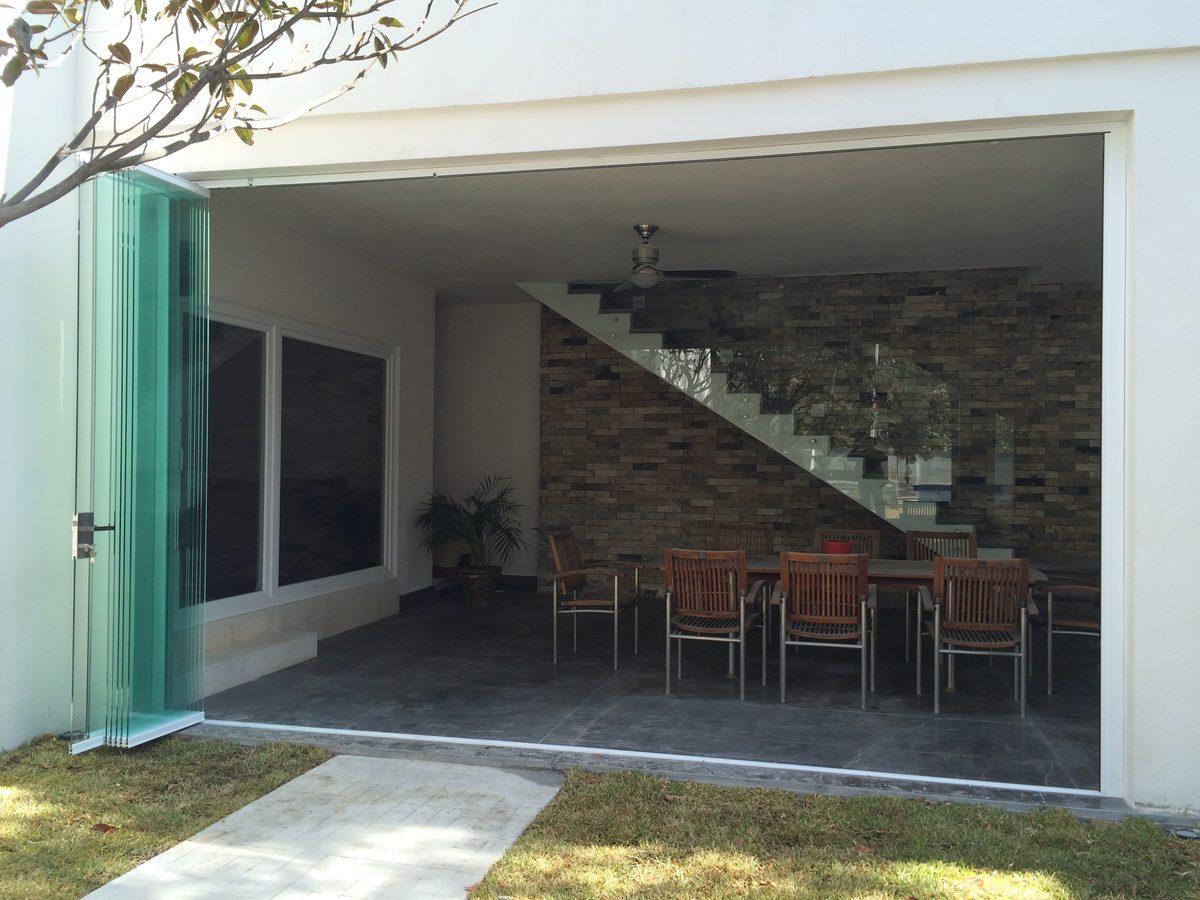 Patio interior con mesa y cortinas de cristal apiladas